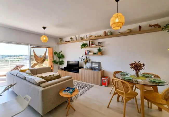 Una luminosa sala de estar y comedor con asientos, un televisor y una mesa de comedor de vidrio.