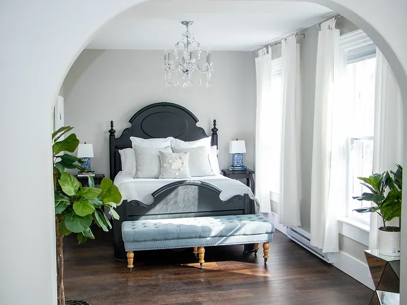 Representative hotel space: A bright bedroom with a dark bed and a bench at its foot.