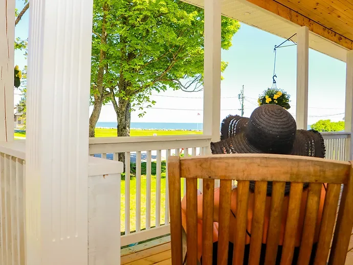 Representative hotel space: A covered porch overlooks a leafy tree and the water.