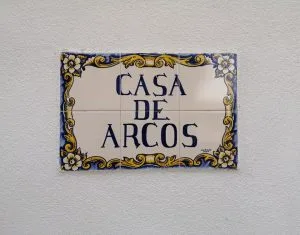 Espacio representativo del hotel: Un letrero decorativo de Casa de Arcos está colocado sobre una pared texturizada.