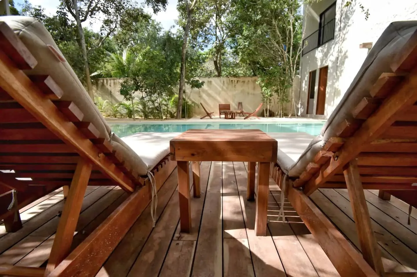 Zona común: Una terraza junto a la piscina con tumbonas de madera y una mesa pequeña.