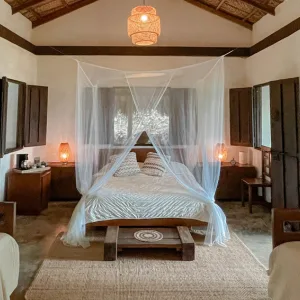 Espacio representativo del hotel: Un dormitorio con una cama con dosel bajo un techo alto con vigas.