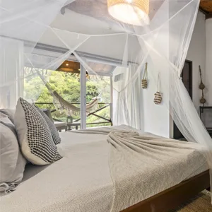 Espacio representativo del hotel: Un dormitorio luminoso con cama con dosel y grandes ventanas con vistas a la vegetación.