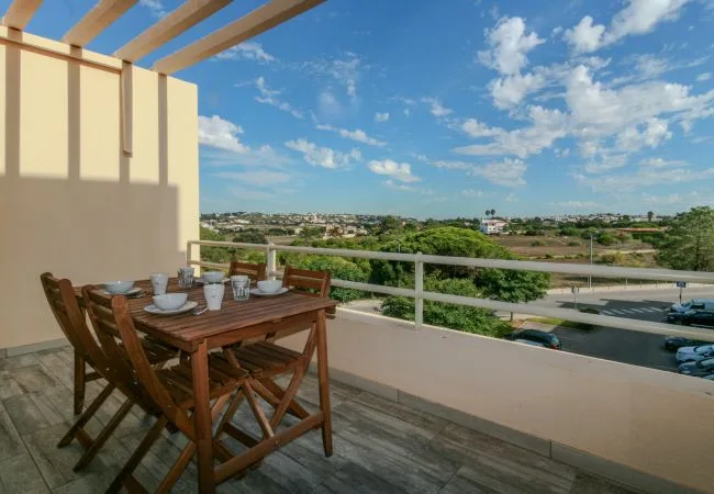 An outdoor dining area with a wooden table overlooking a broad landscape.