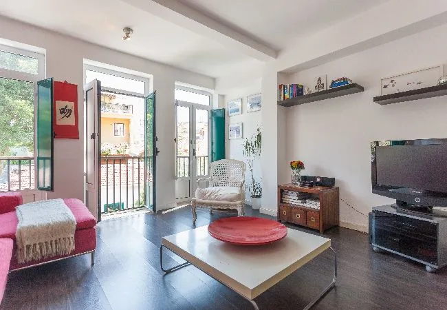 Una sala luminosa con asientos, una mesa de centro y un televisor.