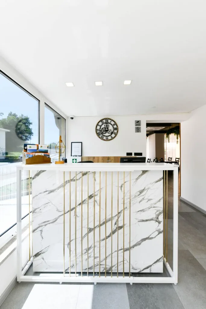 Representative hotel space: A reception desk with a marble-patterned front sits beside large windows.