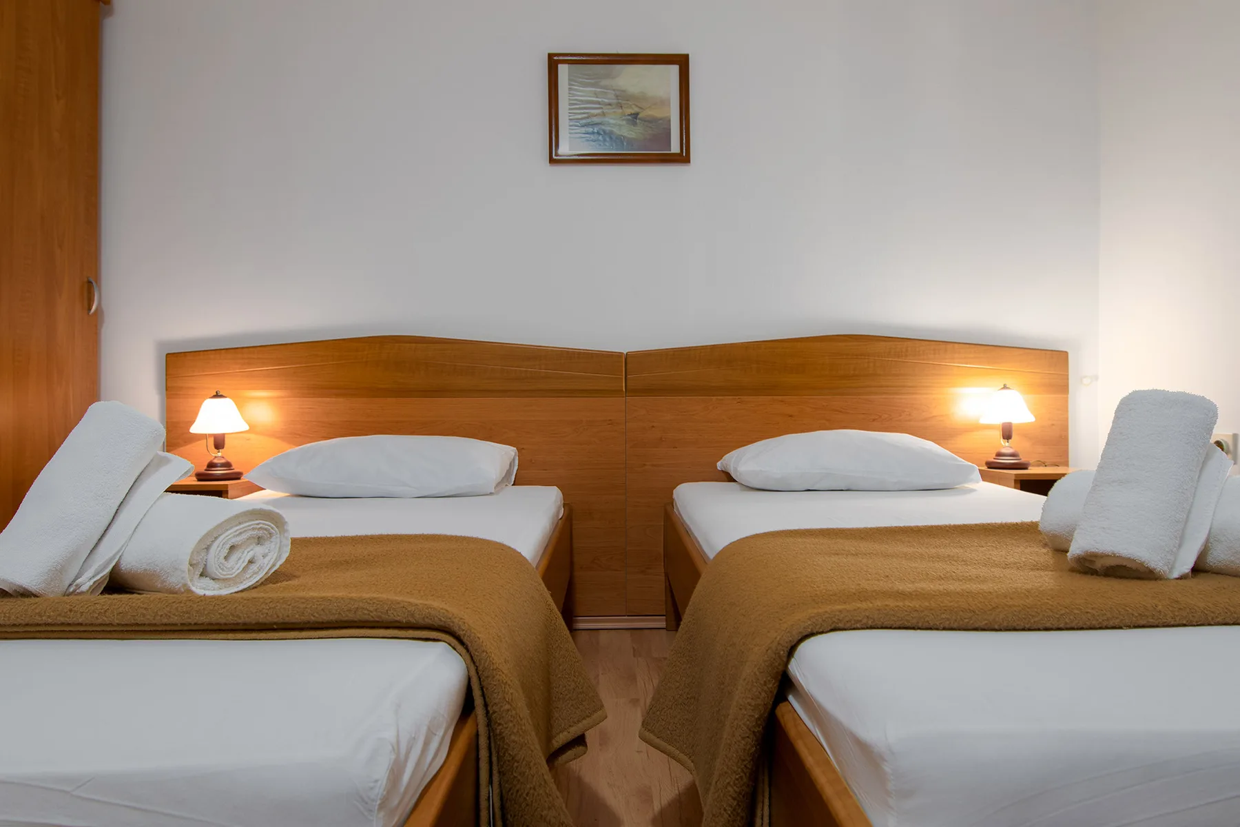 Representative hotel space: A bedroom with two beds and matching wooden headboards.