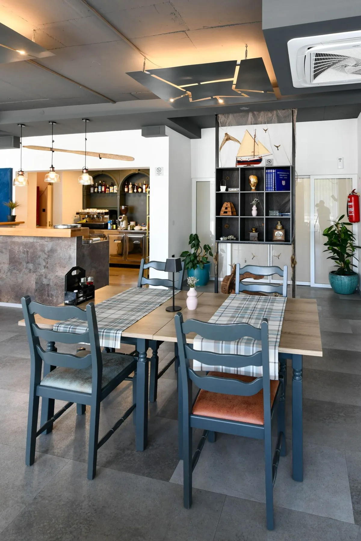 Representative hotel space: A dining area with tables and chairs sits beside a bar and display shelves.