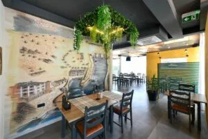 Representative hotel space: A restaurant dining area with tables and chairs beside a large wall mural.