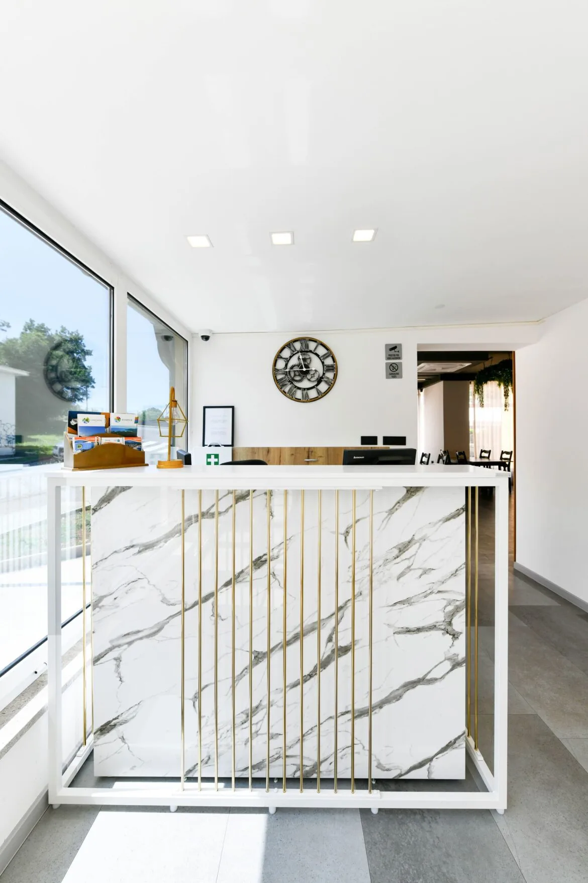 Representative hotel space: A bright reception desk with a veined front and large windows.