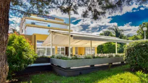 Representative hotel space: A low modern building sits beside a landscaped garden under a tree.