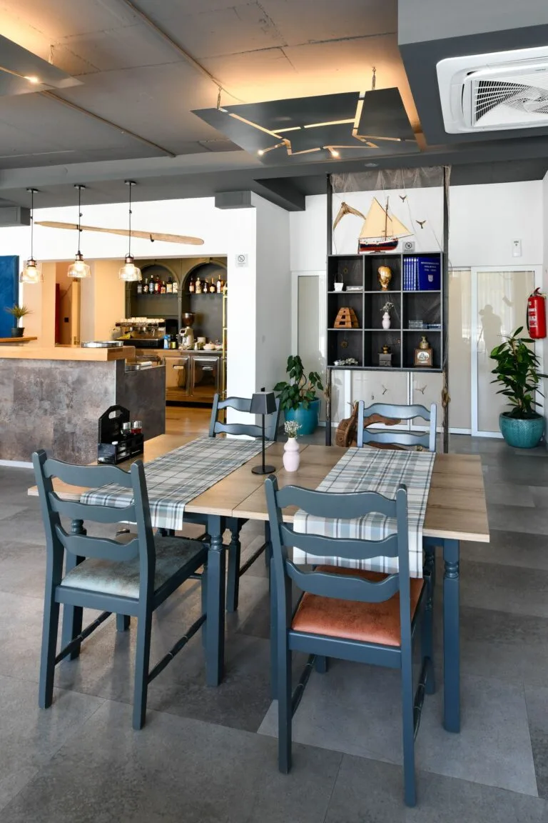 Representative hotel space: A dining area with a long table, blue seating, and a bar behind it.