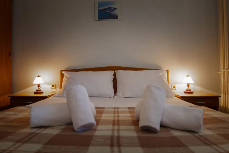 Representative hotel space: A bedroom with a neatly made bed and matching bedside lamps.