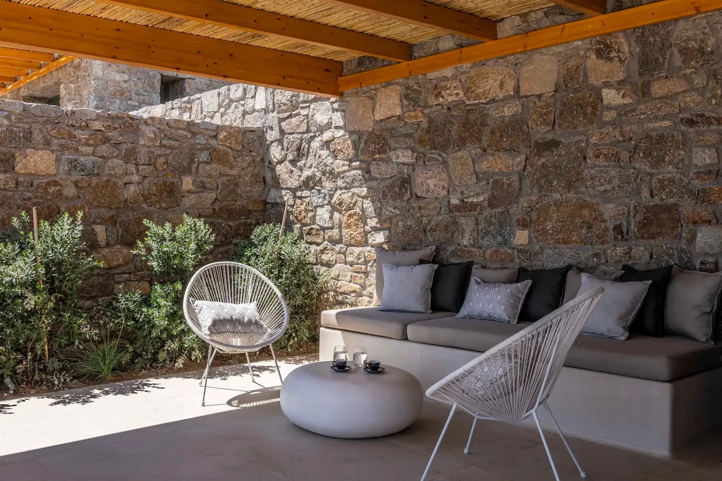 Zona de estar exterior cubierta con una mesa redonda baja y paredes de piedra.