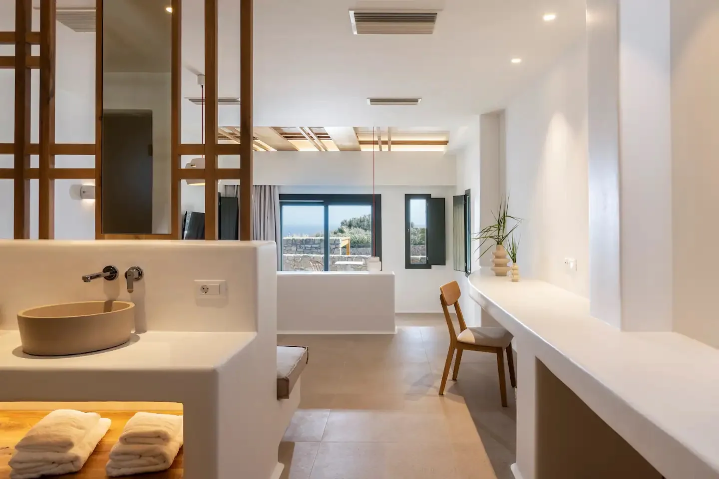 Un baño luminoso con una encimera larga, un lavabo y ventanas al fondo.