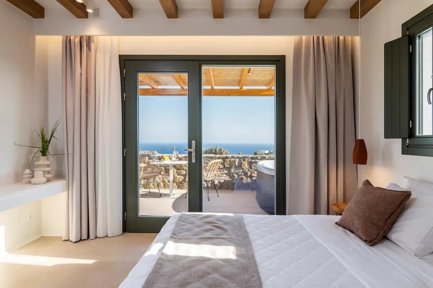 Un dormitorio con una cama frente a puertas de cristal y vistas al mar.