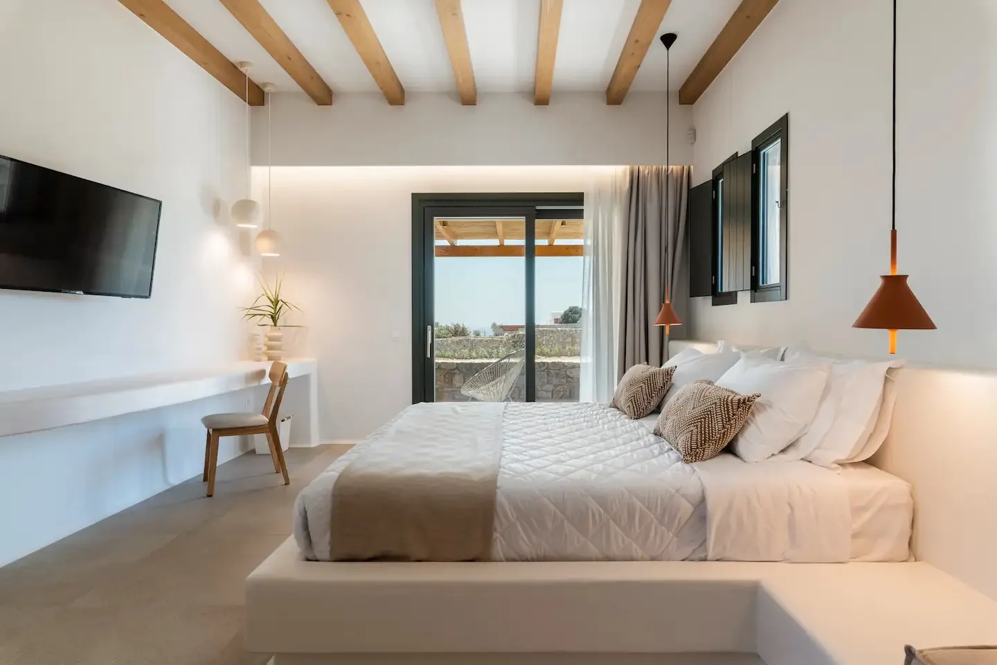 Un dormitorio luminoso con una cama grande y puertas corredizas de vidrio que dan a un balcón.