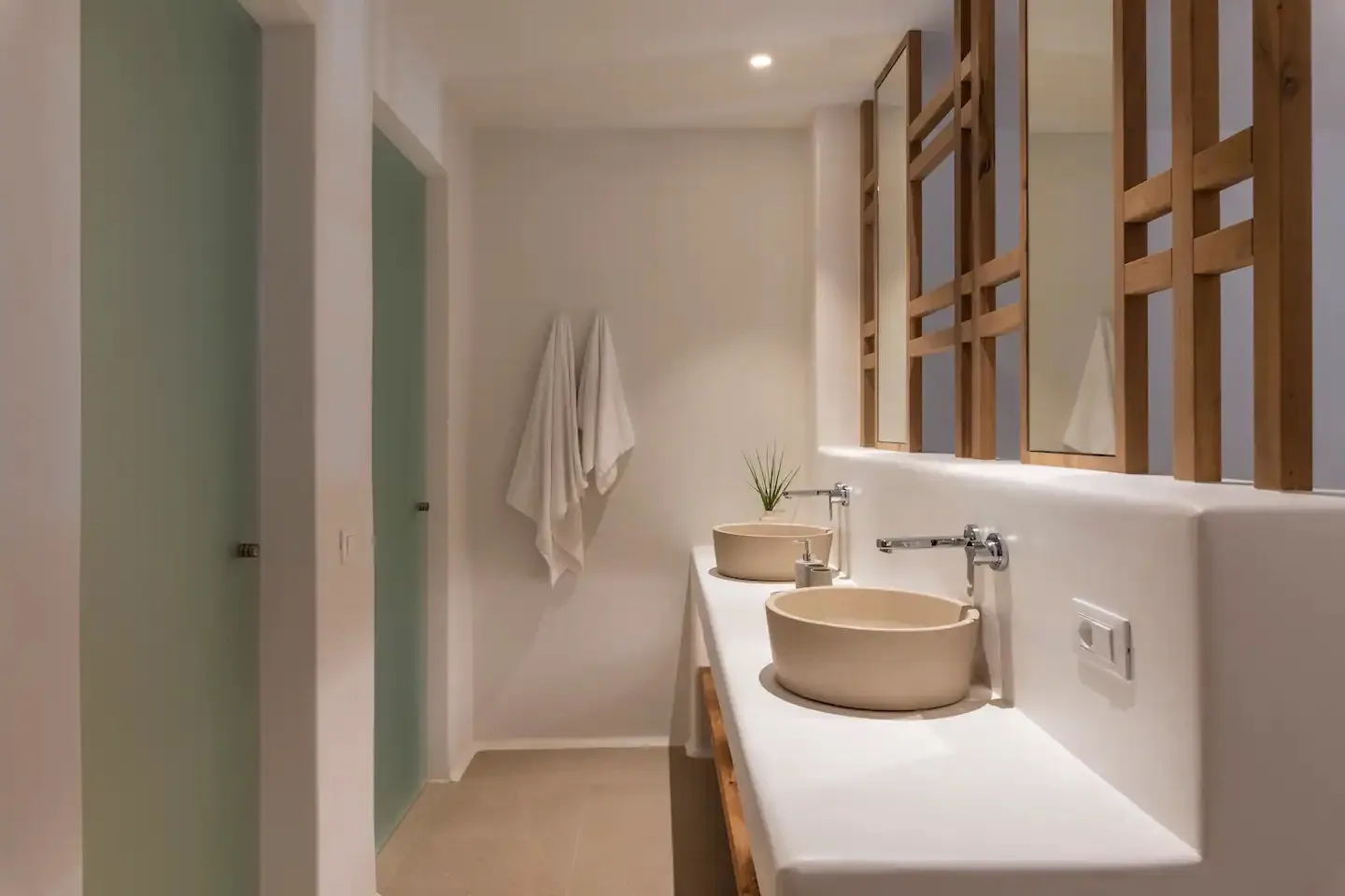 Un tocador de baño con lavabo sobre encimera y espejos con marco de madera.