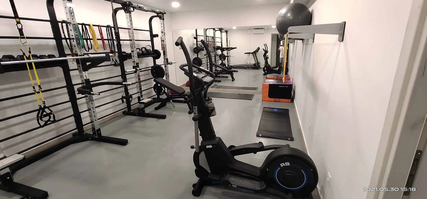 Un gimnasio en casa con aparatos de ejercicio y una fila de cintas de correr.