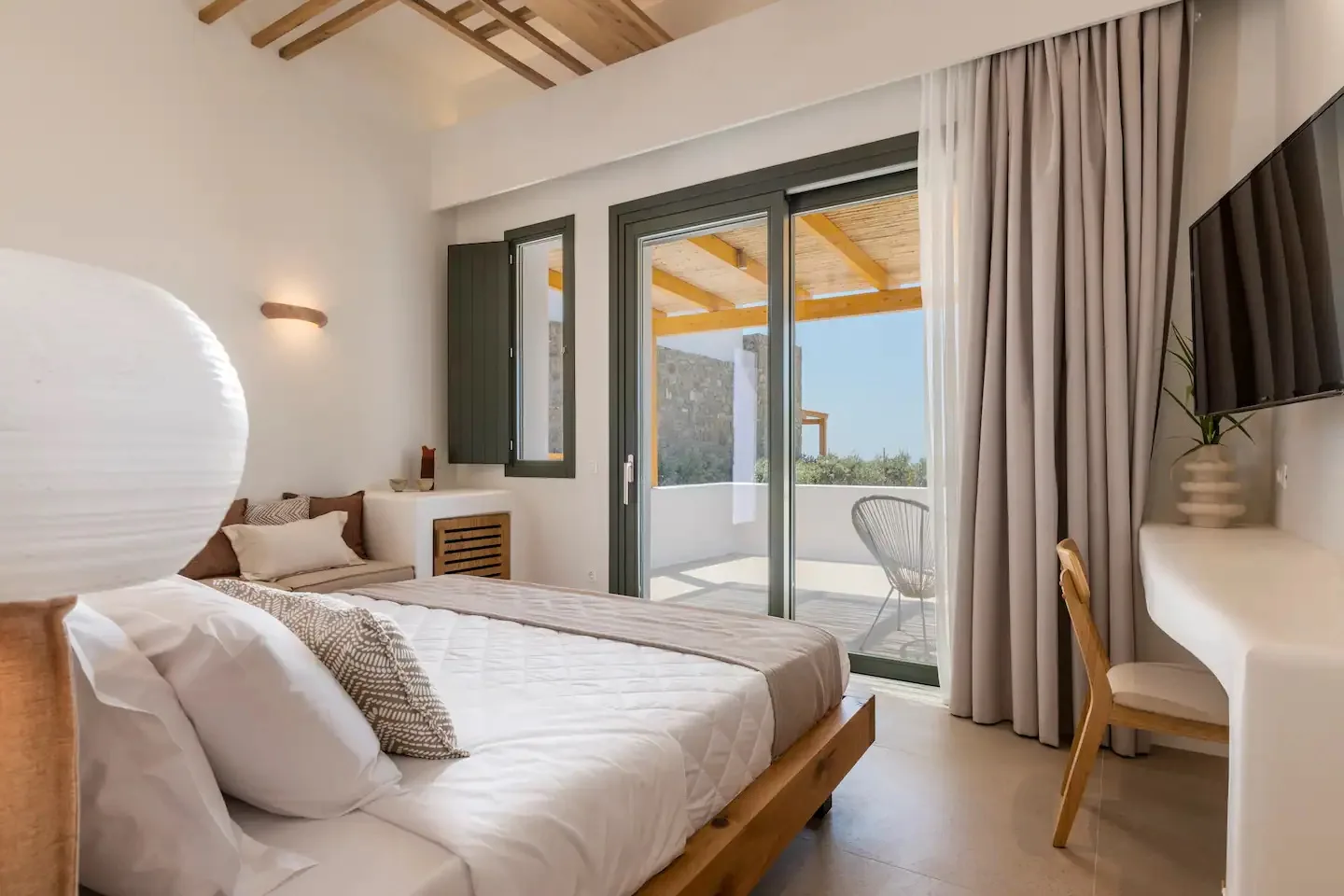 Un dormitorio luminoso con una cama junto a puertas corredizas de vidrio que dan a un patio.