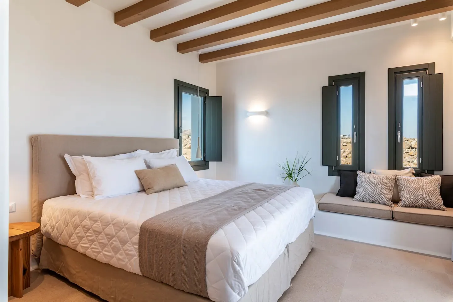 Un dormitorio luminoso con una cama grande y un asiento junto a la ventana.
