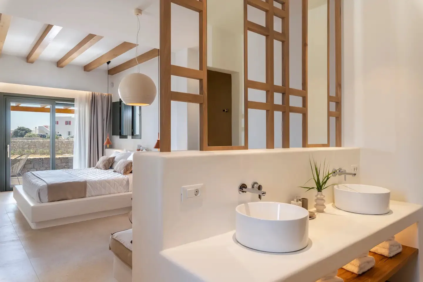 Un dormitorio y una zona de lavabos comparten un espacio abierto, con una cama junto a los lavabos.