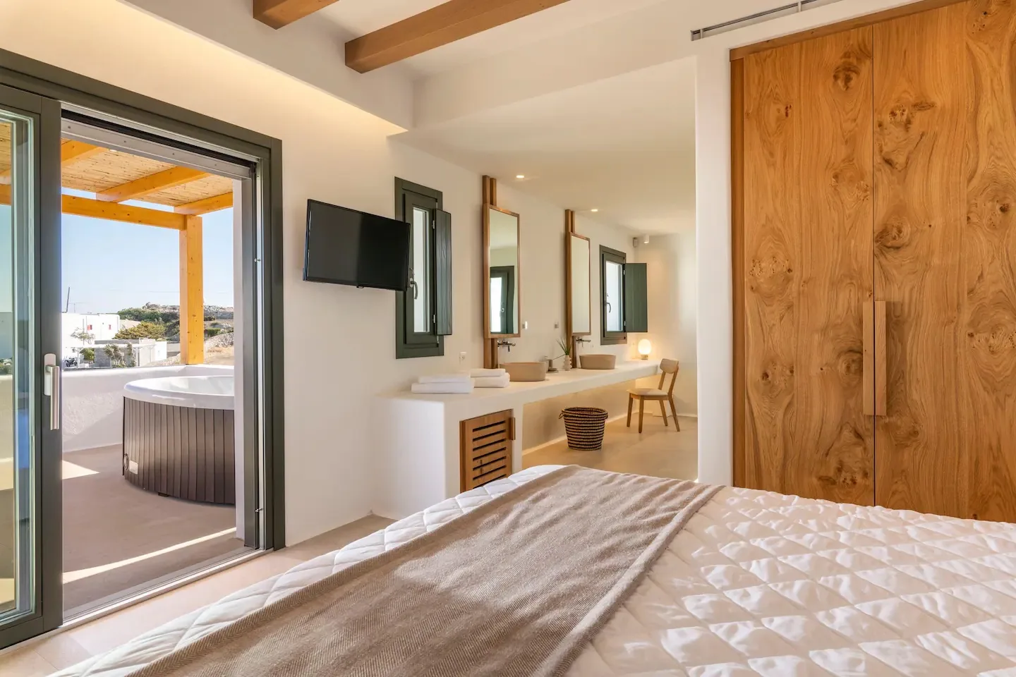 Un dormitorio con cama, armario de madera y tocador junto a una puerta abierta al patio.