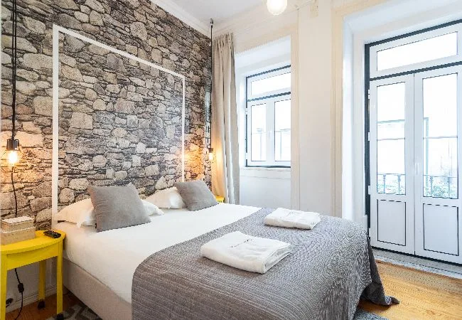 Un dormitorio con una cama bien hecha y una pared decorativa con aspecto de piedra.