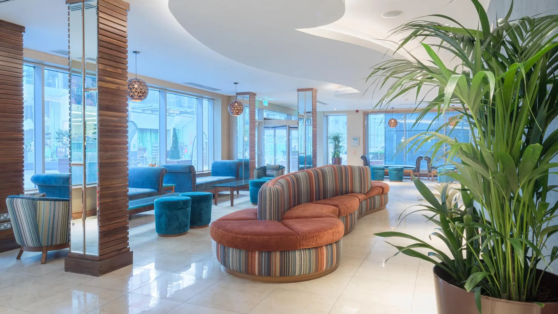 Representative hotel space: A bright hotel lounge has colorful seating beside large windows.