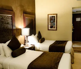 Espacio representativo del hotel: Un dormitorio de hotel con dos camas, lámparas de mesita y cuadros en la pared.