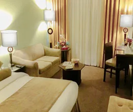 Espacio representativo del hotel: Un dormitorio de hotel con una cama, asientos y una mesa pequeña.