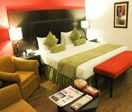 Espacio representativo del hotel: Un dormitorio de hotel con una cama grande, lámparas de noche y un sillón tapizado.