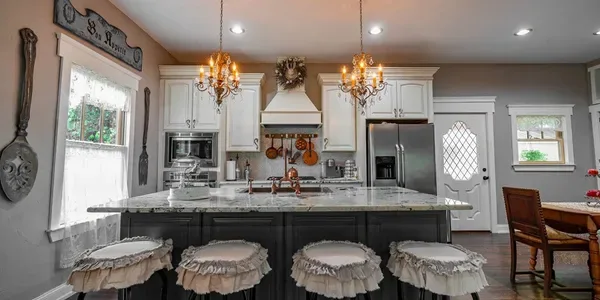 Representative hotel space: A bright kitchen features a central island, white cabinets, and hanging chandeliers.