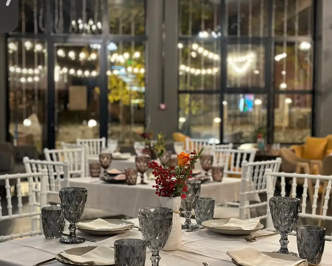 Espacio representativo del hotel: Un comedor está dispuesto con mesas, cristalería y asientos blancos.