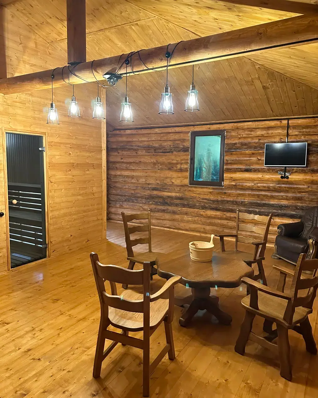 Espacio representativo del hotel: Un comedor revestido de madera con una mesa, sillas y luces colgantes.
