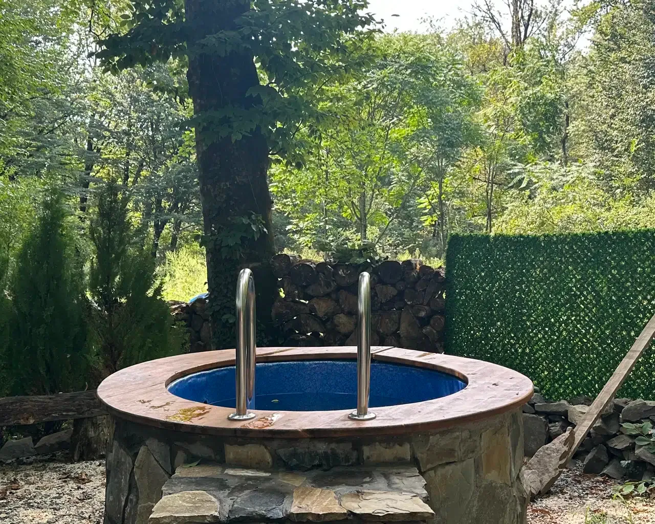 Espacio representativo del hotel: Un jacuzzi al aire libre está rodeado de árboles y muros de piedra.