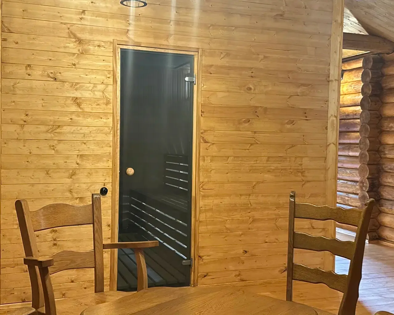 Espacio representativo del hotel: Una habitación con paredes de madera, una puerta oscura y asientos de madera.