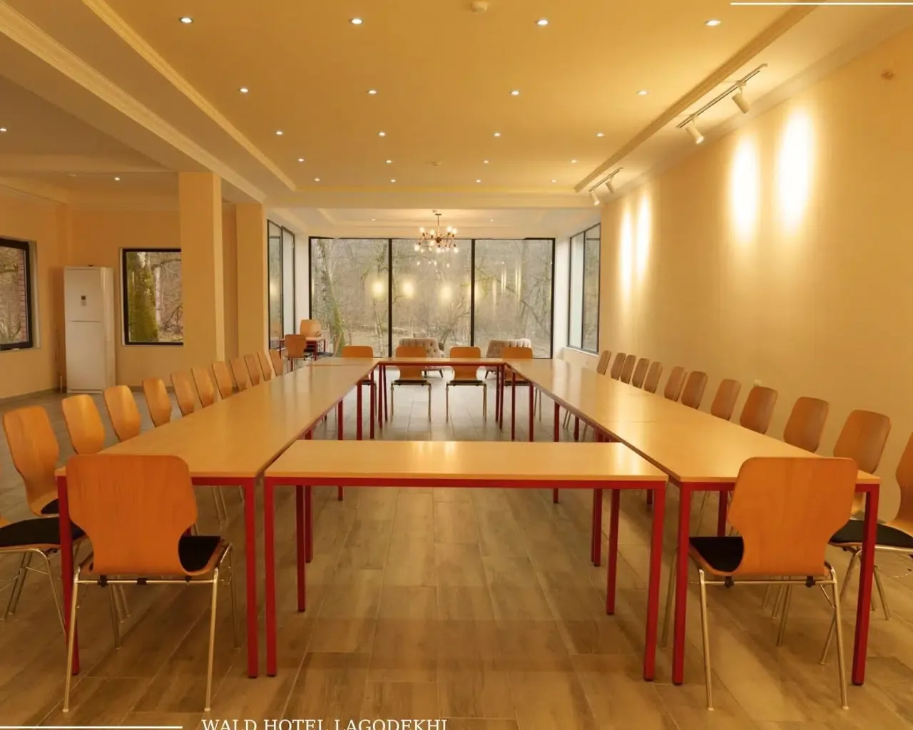Espacio representativo del hotel: Una sala de conferencias con mesas largas y filas de asientos.