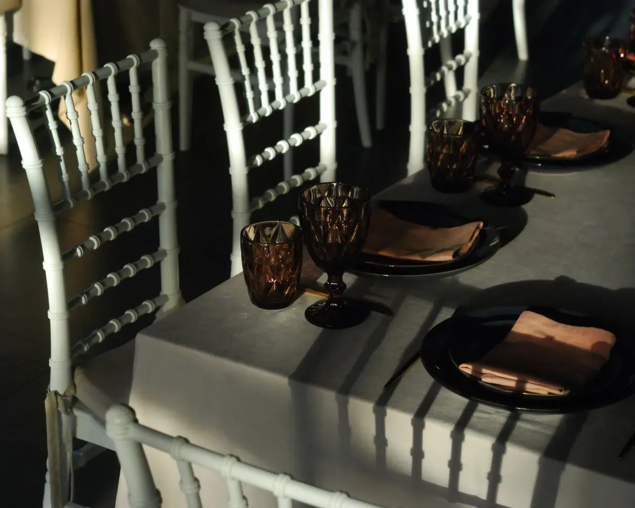 Espacio representativo del hotel: Una mesa de comedor está preparada con cristalería oscura y servilletas dobladas.
