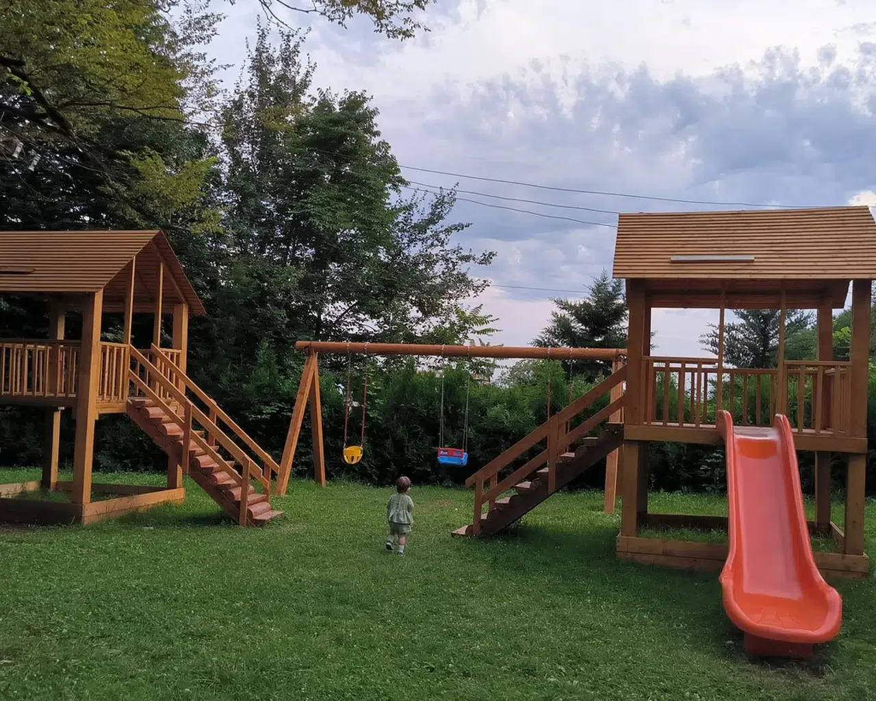 Espacio representativo del hotel: Un parque infantil al aire libre con estructuras de madera, un columpio y un tobogán.