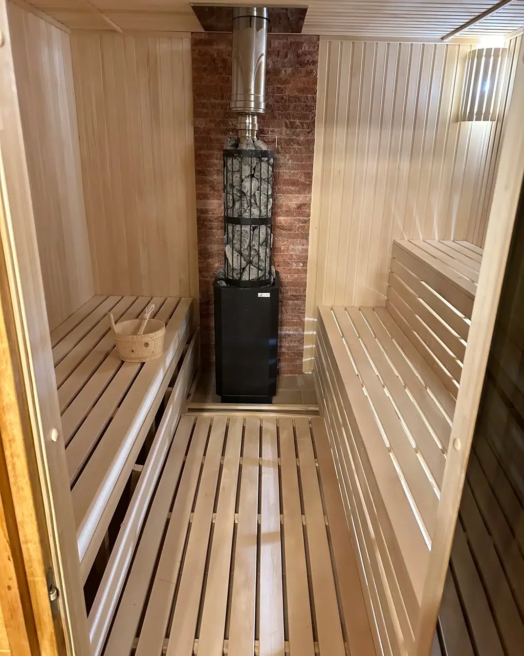 Espacio representativo del hotel: Una sauna de madera con bancos escalonados y un calentador central.