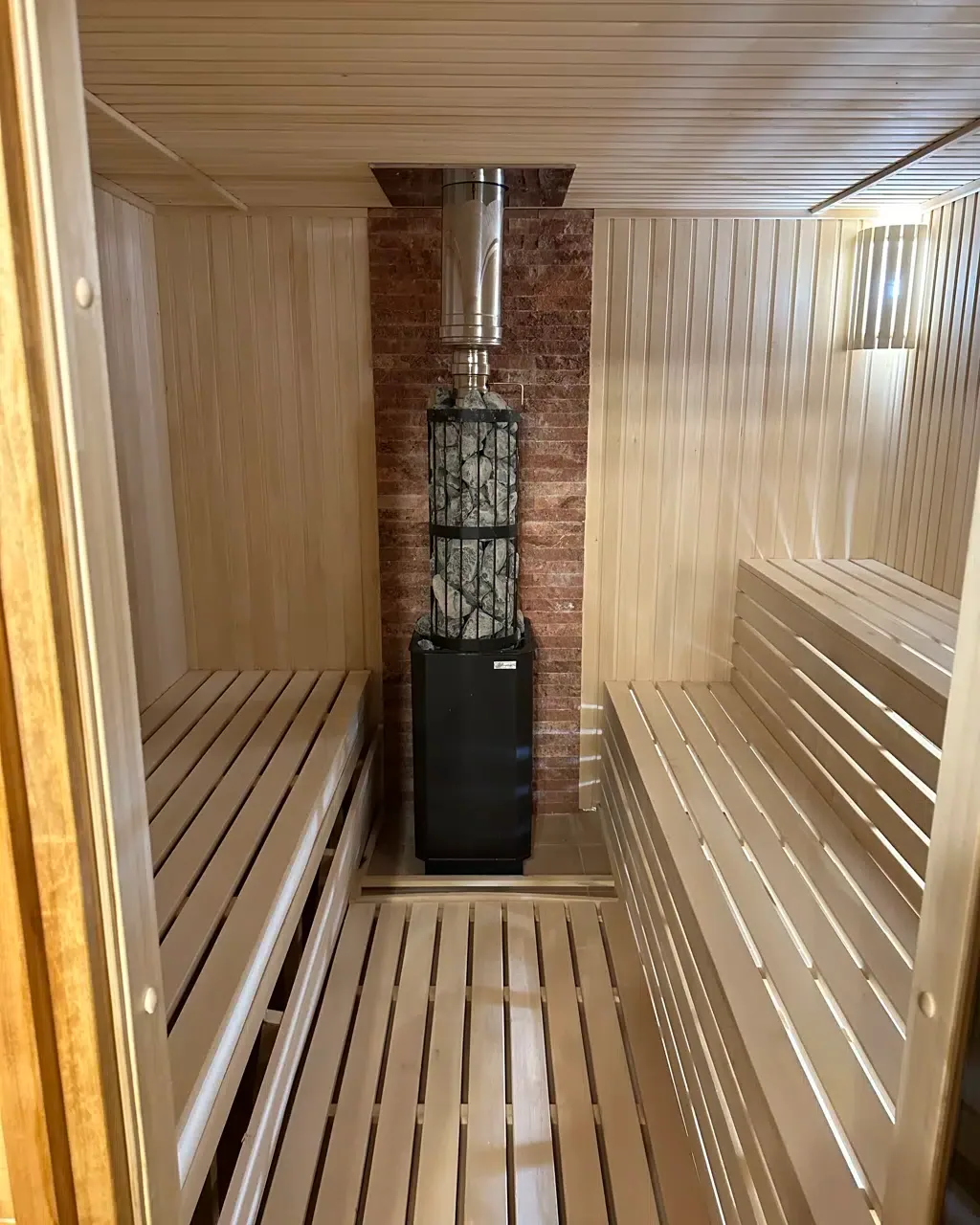 Espacio representativo del hotel: Sauna revestida de madera con bancos escalonados y una estufa central.
