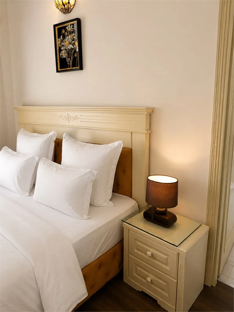 Espacio representativo del hotel: Un dormitorio con una cama tendida y una mesita de noche con una lámpara.