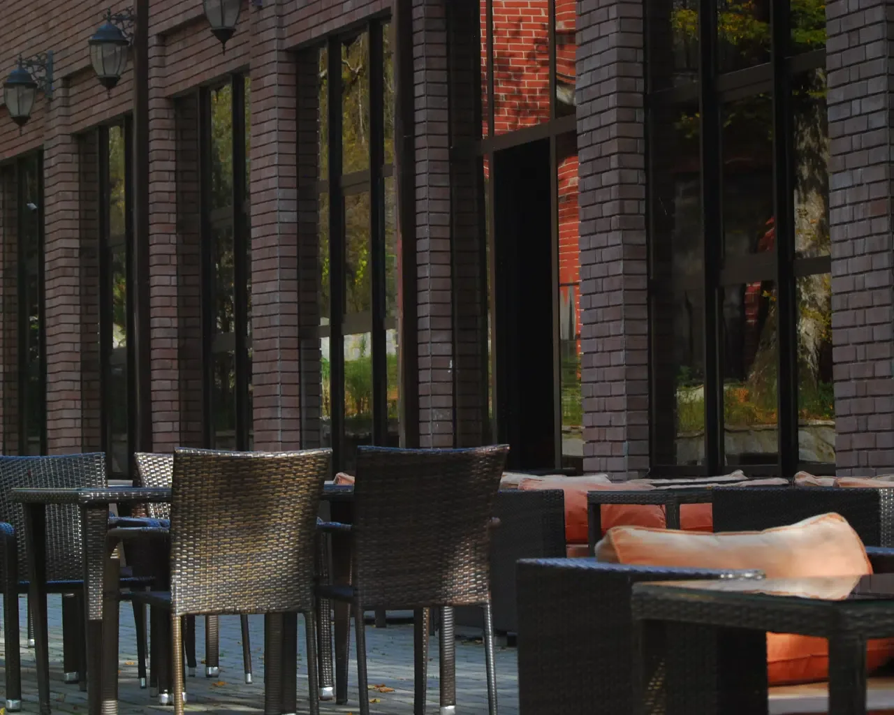 Espacio representativo del hotel: Asientos en un patio exterior junto a un edificio de ladrillo con ventanas altas.