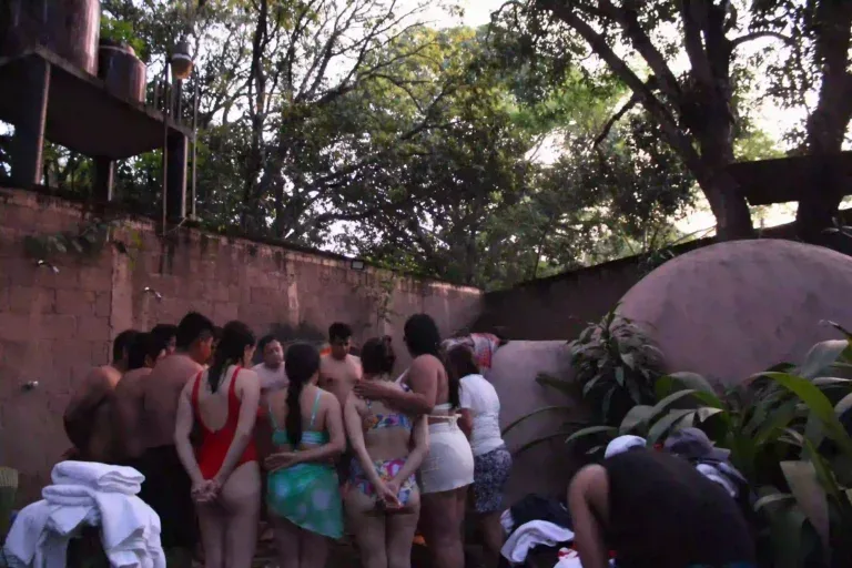 Representative hotel space: People gather in an outdoor bathing area beside a stone wall and trees.