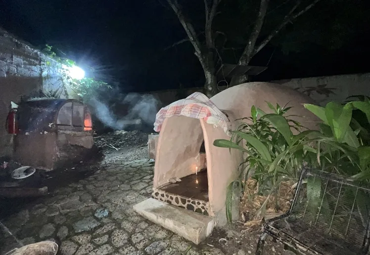 Representative hotel space: A small outdoor oven stands beside a stone-paved area at night.