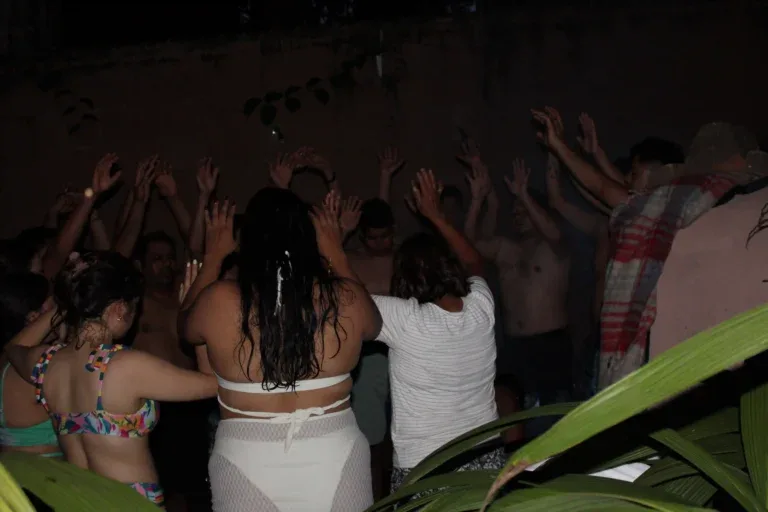 Representative hotel space: A group of people dance with their hands raised in a dimly lit gathering.