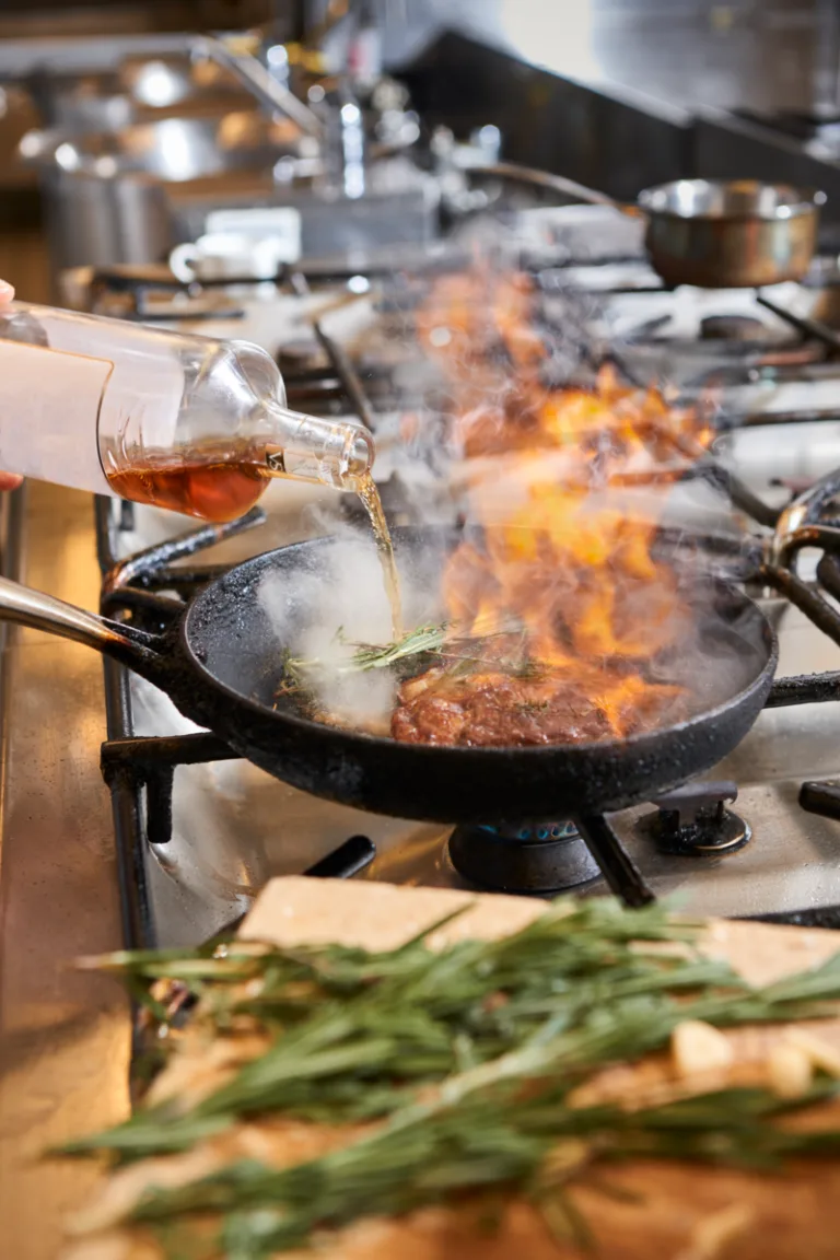 Representative hotel space: A commercial kitchen scene shows food cooking in a pan over an open flame.