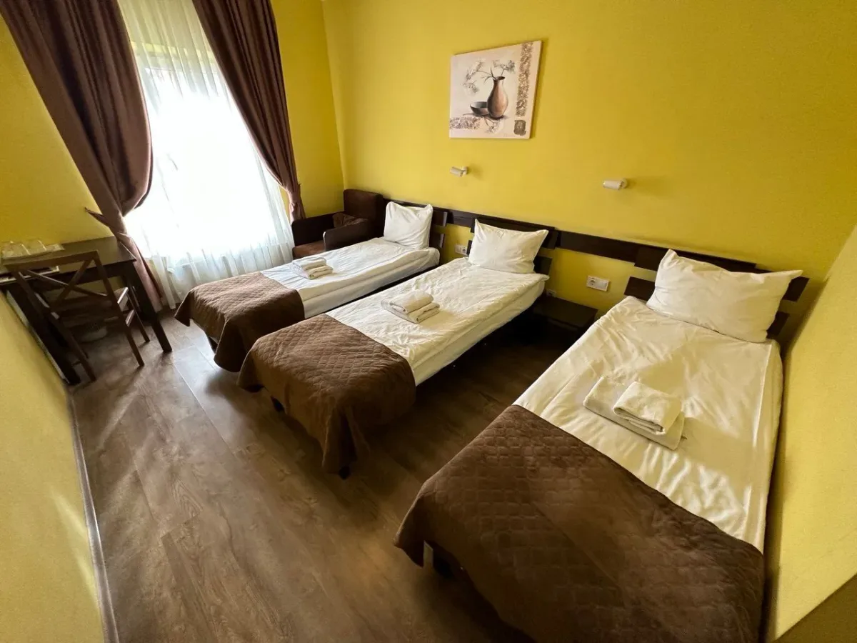 Espacio representativo del hotel: Un dormitorio con tres camas individuales y paredes amarillas.