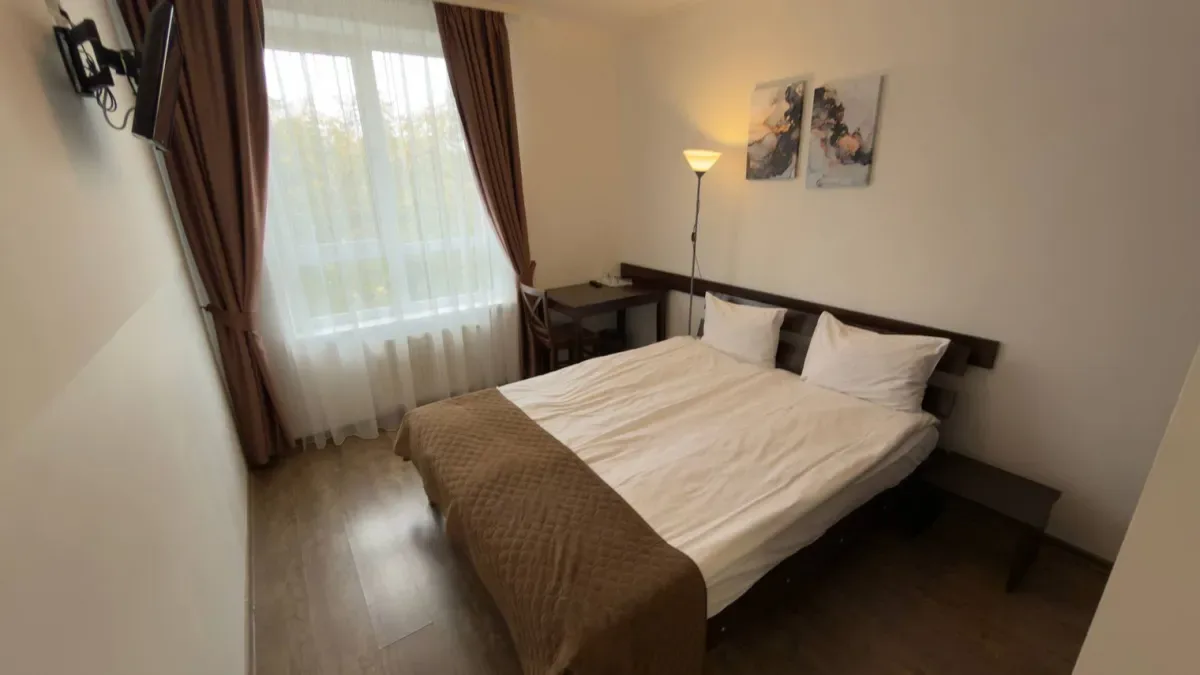 Espacio representativo del hotel: Un dormitorio con una cama junto a una ventana con cortinas.